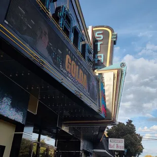 people walking on the sidewalk in front of the theater
