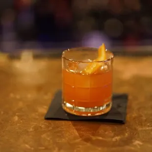 a glass of orange drink on a coaster