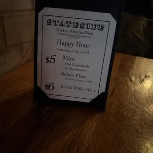 a happy hour sign on a table