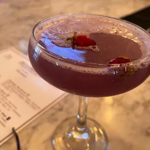 a purple cocktail in a coupe glass