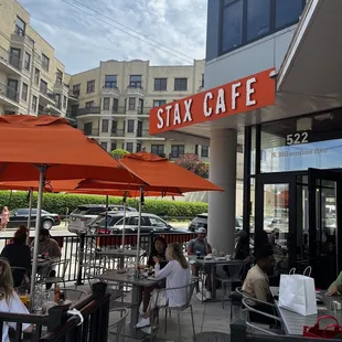 people sitting at tables with orange umbrellas