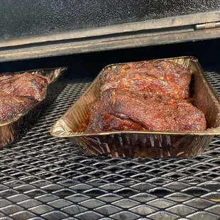 two trays of meat on a grill