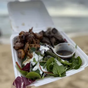a hand holding a takeout box of food