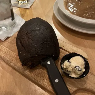 a steak on a cutting board with a knife and a bowl of soup