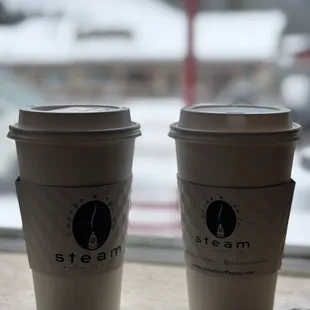 two coffee cups sitting on a window sill