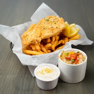 a basket of fish and fries with a side of dips