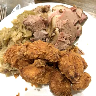 a plate of fried chicken, mashed potatoes, and sauerkraut