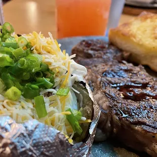 Rib Eye Steak comes with 2 sides (Salad - not pictured, Baked Potato) and Garlic Bread