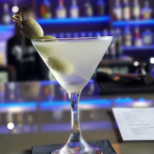 a martini with a green olive garnish