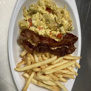 Revuelto con vegetales y tocino al lado y papas fritas  Scrambled eggs with veggies bacon on the side and house potatoes