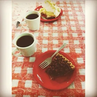 a red plate with a piece of pie and two cups of coffee