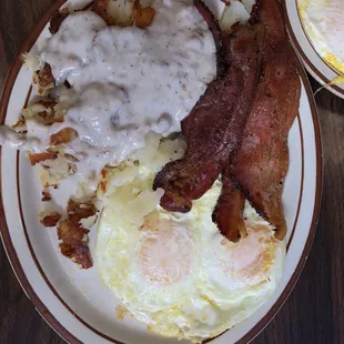 a plate of eggs, bacon and gravy