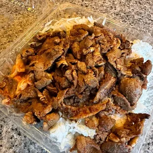 ows a plastic container filled with meat and rice