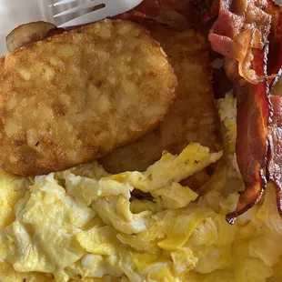 a plate of eggs, hash browns and bacon