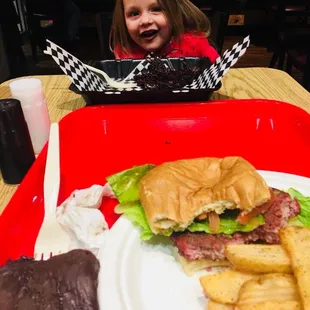 a little girl sitting at a table with a plate of food