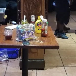 Condiment table with someone's purse and drink