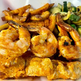 Chicken and shrimp skewers with mixed vegetables and fries.