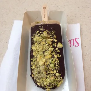 Coffee gelato stick dipped in dark chocolate with pistachio