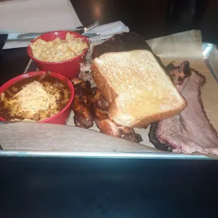 a tray of food including a sandwich, macaroni, and cheese