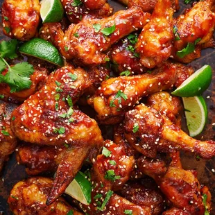 a plate of chicken wings with lime wedges