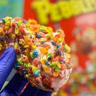 a hand holding up a candy covered donut