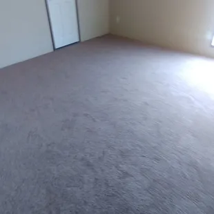 an empty room with a fan in the corner