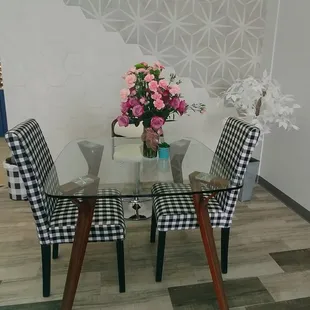 a glass table with four chairs and a vase of flowers