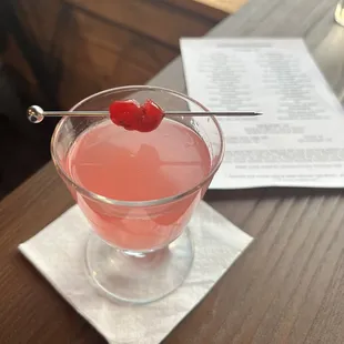 a pink drink with a cherry on a spoon