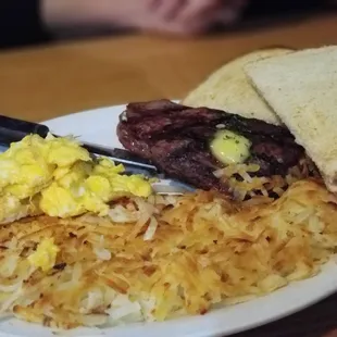 Steak and scrambled eggs with hash and sourdough.