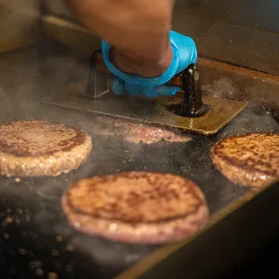 a person cooking hamburgers on a grill