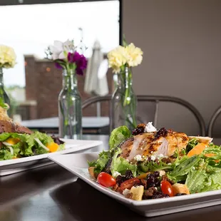 two plates of salad and a vase of flowers