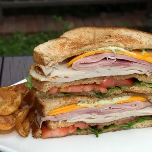 a ham, cheese, tomato, and lettuce sandwich with potato chips