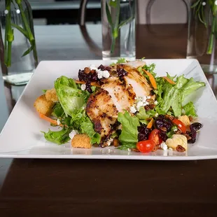 a plate of salad with chicken and croutons
