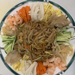 a plate of noodles, shrimp, and carrots