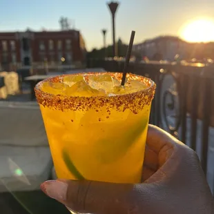 a hand holding a glass with a drink in it