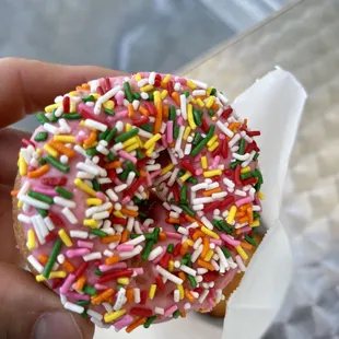 a hand holding a sprinkled donut