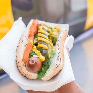 a person holding a hot dog with mustard and ketchup