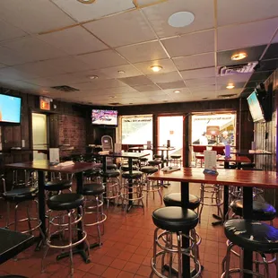 a bar with stools and televisions