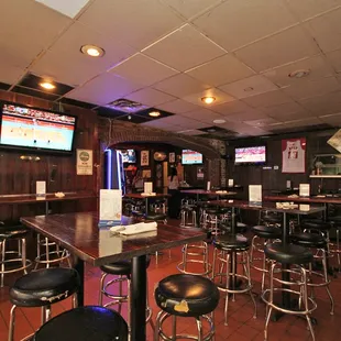 a bar with stools and televisions