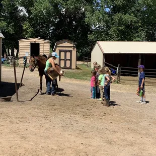 Kids learning how to put on a saddle