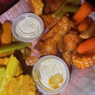 a tray of chicken wings, carrots, corn, and celery