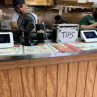 a man standing behind a counter with a fan