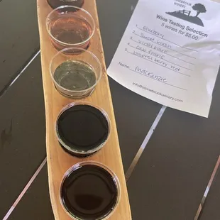 a wooden paddle with five different types of wine