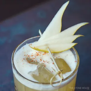 a drink with a pear garnish