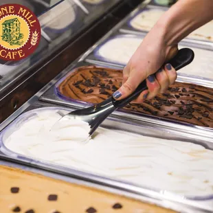 a person scooping ice cream into trays