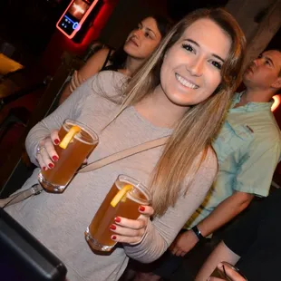 a woman holding two beer glasses