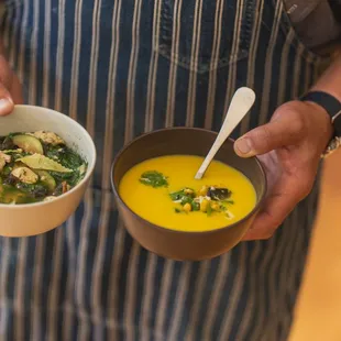 a man holding two bowls of soup