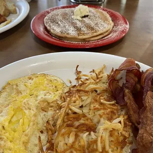 Blueberry pancakes, over hard eggs, hash  browns and bacon.