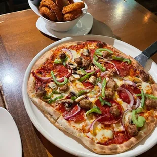 a pizza with pepperoni, onions, mushrooms, and cheese