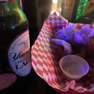 Bottle of yuengling and a patty melt with fresh onion rings.
